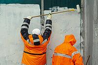 Workers paint wall. Wall flogging. Orange clothing of the workers. Graffiti smear. Fight against vandalism [IBR125557566]