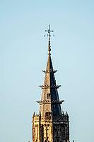 The detailed spire of Toledo Cathedral against a clear sky displays intricate stonework and a weather vane, showcasing Spanish architectural heritage [IBR125557574]