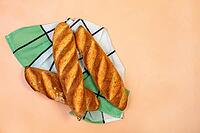 Three freshly baked traditional baguettes on the background of the color of powder with copy space. Top view, flat lay. French cuisine [IBR125557585]