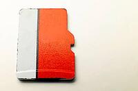 Top view of unrecognizable red and white micro sd flash drive on white background. Used flash drive with scuffs concept of old storage media [IBR125557620]