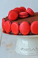 Chocolate cake decorated with macarons on a white wooden table [IBR125557621]