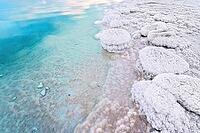 Sand completely covered with crystalline salt on the shore of the Dead Sea, turquoise blue water nearby - typical scenery on a beach in A Bokek, Israel [IBR125566000]