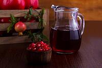 Pomegranate juice and fruits on dark wooden background, selective focus [IBR125566010]