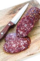 Sliced dry sausage and knife on a white background [IBR125566018]