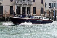 A Carabinieri boat sails through a Venetian canal with a powerful bow wave on historic buildings, Venice, Veneto, Italy [IBR125566037]