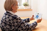 Reindeer elderly senior woman talking to GP doctor about virtual telemedicine video call, holding tablet computer, female doctor giving consultation over laptop computer screen, remote appointment at home [IBR125566040]