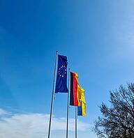 Flags of Ukraine, Germany and European Union fly side by side against blue sky [IBR125566061]