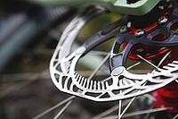 Close-up of Hydraulic bicycle disc brakes, gray metal disc attached to a bicycle wheel close-up, effective popular mountain bike brakes. Bicycle spokes on a gray background [IBR125566067]