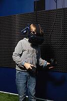 6 years old boy in virtual helmet learning how to control game with controllers [IBR125566079]