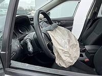 Dust coats the dashboard and door trim around the inflated airbag, with the empty front seats and center console visible inside the car cabin, AI generated [IBR125592710]