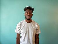 Studio portrait of a surprised young man with dreadlocks wearing a white t-shirt against a light green background, AI generated [IBR125592713]