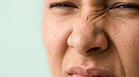 Close-up of adult scrunched nose with wrinkles across the bridge and raised upper lip, nose wrinkler muscle action, cropped face, copy space, AI generated [IBR125592728]