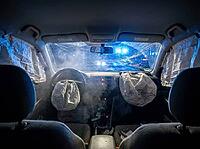 Dust and deployment residue linger around the dashboard as bright blue lights show beyond the fractured windshield, with debris scattered across the cabin, AI generated [IBR125592729]