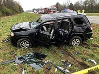 Shattered glass and vehicle debris cover the grassy shoulder while a fire engine and flashing emergency lights appear along the road nearby, AI generated [IBR125592730]