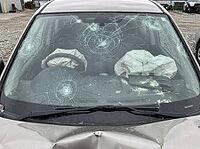 Impact fractures spread across the windshield, with both front airbags inflated and glass fragments visible on the dashboard and hood, AI generated [IBR125592739]
