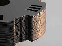 Precision-cut steel sheets reveal fine layered edges and punched slots, with a smooth metallic finish set against a plain background in a detailed close-up, AI generated [IBR125592744]