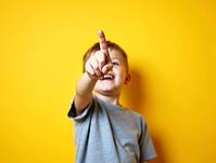 Young boy pointing up with index finger smiling on yellow background, AI generated [IBR125592749]