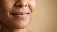 Close-up of adult woman's mouth with lip corners pulled upward in a gentle closed smile, lip corner puller muscle action, cropped face, copy space, AI generated [IBR125592750]