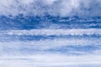Aircraft condensation contrails in the blue sky inbetween some beautiful clouds [IBR125606076]