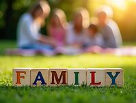 Colorful wooden alphabet blocks spelling the word family placed on green grass with a blurred family enjoying a picnic in the background, AI generated [IBR125621280]