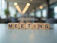 Wooden cubes spelling meeting are placed on a reflective table in a blurred office background, symbolizing business communication and teamwork, AI generated [IBR125621284]