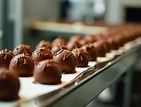 Round chocolate pralines moving along an assembly line, illustrating the production process in a food factory, AI generated [IBR125621291]