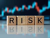 Four wooden cubes spelling risk reflecting on a table with blurred stock market chart in background, AI generated [IBR125621294]