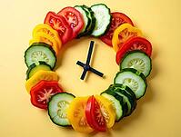 Sliced cucumbers, tomatoes, and peppers arranged as a clock on a yellow background, promoting healthy eating habits and mindful meal timing, AI generated [IBR125621312]