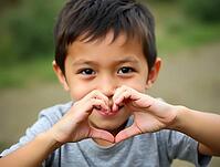 Adorable little boy making a heart shape with his hands, smiling shyly, AI generated [IBR125621317]