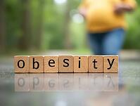 Wooden blocks spelling obesity with pregnant woman exercising in background, illustrating risks of obesity during pregnancy, AI generated [IBR125621320]
