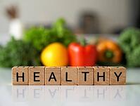 Wooden blocks spelling the word healthy with fresh vegetables in the background promoting a healthy lifestyle, AI generated [IBR125621336]