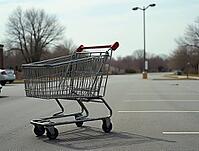 Metal shopping cart stands alone in deserted parking lot, suggesting decline in consumer spending and retail activity, AI generated [IBR125621361]