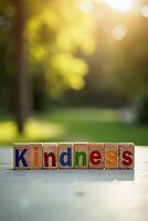 Colorful wooden toy blocks spelling kindness with a blurred park background and bright sunlight bokeh, AI generated [IBR125621368]