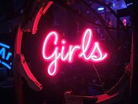 Vibrant neon girls sign glowing at nightclub entrance, creating exciting and seductive atmosphere, AI generated [IBR125636914]