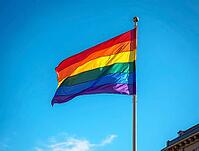Rainbow flag waving in the wind against a clear blue sky, representing LGBTQ+ pride, diversity, and inclusion, AI generated [IBR125636915]