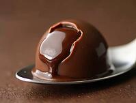 Cracked chocolate praline on spoon, revealing rich ganache filling, tempting indulgence, AI generated [IBR125636921]