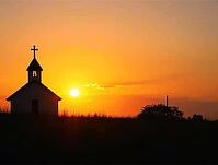 Serene countryside church stands silhouetted against a vibrant sunrise, its cross reaching towards the golden sky, AI generated [IBR125636927]