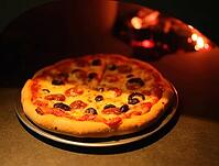 Freshly baked pizza with pepperoni and black olives coming out of a traditional wood-fired oven, AI generated [IBR125636930]