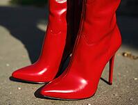 Close-up of glamorous shiny red patent leather high heel boots standing on gray pavement, AI generated [IBR125636935]