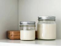 Organic beauty products in glass jars with metal lids on a minimalist bathroom shelf, AI generated [IBR125636936]