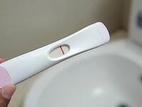 Positive pregnancy test result is held by a hand in a bathroom setting, AI generated [IBR125636938]
