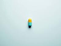 Yellow and light blue capsule resting on a sterile white surface, representing medication, healthcare, and pharmaceutical concepts, AI generated [IBR125636957]