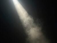Particles of dust floating gently through a narrow beam of sunlight piercing a dark room, AI generated [IBR125636961]