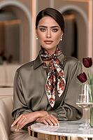 Woman wearing red and navy floral silk scarf tied at neck, olive green satin blouse, seated at marble bistro table with burgundy tulips. AI generated [IBR125645868]