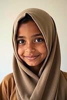 Studio portrait of a smiling young muslim girl wearing a traditional headscarf, showcasing her cultural identity, AI generated [IBR125645911]