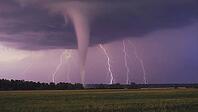 Dramatic scene of a tornado forming during a powerful thunderstorm, with lightning illuminating the sky over a field, AI generated [IBR125653416]