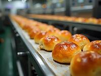 Golden brown buns travel on a conveyor belt, showcasing the automated production process in a bakery or food factory, AI generated [IBR125653422]