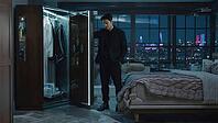 Businessman choosing clothes from futuristic smart wardrobe in his luxury penthouse bedroom with night city view, AI generated [IBR125653433]