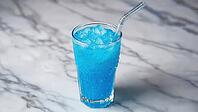 Glass filled with intensely blue carbonated soft drink, ice cubes glistening, and a straw resting on a white marble surface, exuding refreshment, AI generated [IBR125653445]