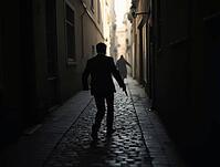 Undercover agent escaping through dark alley with gun, mysterious silhouette chasing, AI generated [IBR125653456]